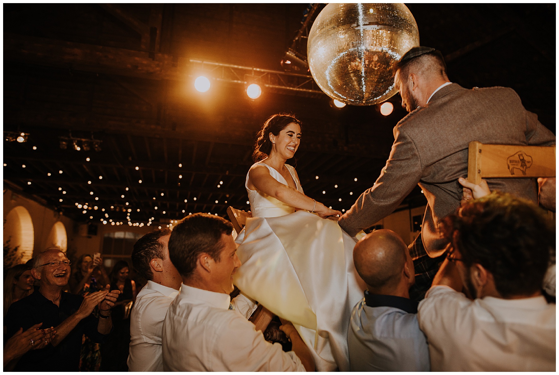 a bride and groom are held aloft on chairs